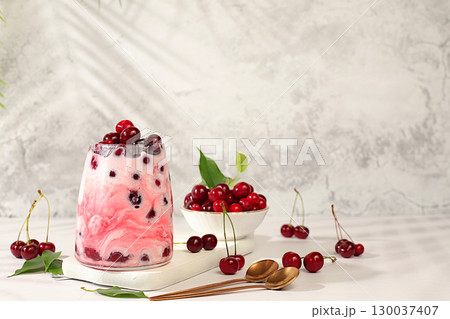 Modern still life with berries and drinks. Cherry yogurt with berries in a glass on an elegant table, fruit salad, detox diet and natural nutrition concept, healthy breakfast with ingredients Modern still life with berries and drinks. Cherry yogurt with berries in a glass on an elegant table, fruit salad, detox diet and natural nutrition concept, healthy breakfast with ingredients 130037407