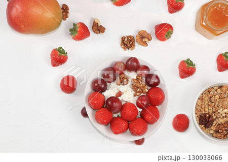 Strawberry yogurt, granola, cottage cheese, fresh berries, mangoes, strawberries and grapes on a light table. The concept of healthy and natural food. Useful breakfast, food for children, selective 130038066