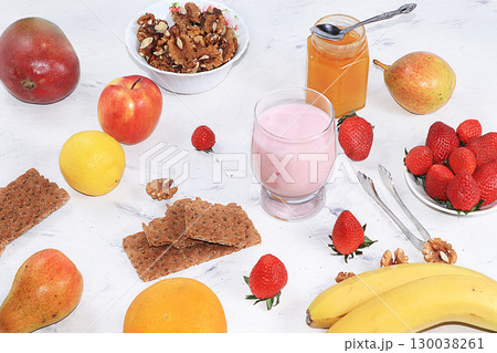 Useful breakfast. Strawberry smoothie, cocktail, granola, fresh berries and fruits, bananas, mangoes and pears on a gray concrete background. The concept of healthy and natural food, detox diet, food Useful breakfast. Strawberry smoothie, cocktail, granola, fresh berries and fruits, bananas, mangoes and pears on a gray concrete background. The concept of healthy and natural food, detox diet, food 130038261