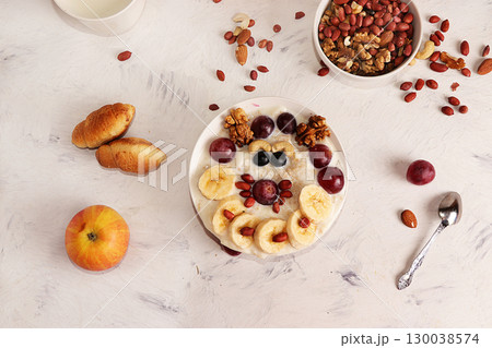 Healthy natural breakfast, funny food for children. Oatmeal with grapes, nuts and honey, top view, selective focus. Healthy eating concept. 130038574