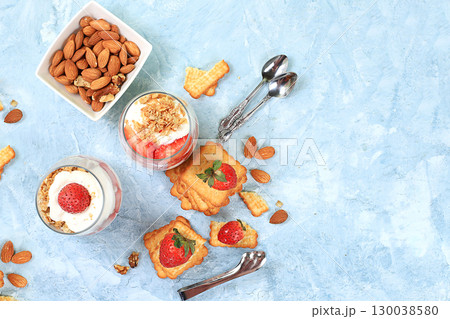 Strawberry yogurt with berries, crackers and muesli on a bright table, fruit salad. Healthy breakfast with ingredients, natural food concept, lifestyle, food for children, selective focus, top view, 130038580