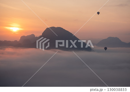 Hot air balloons flying over misty mountains at sunrise with scenic landscape   at  Phadeng Peak, Luang Prabang, Laos 130038833