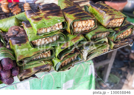 Traditional grilled sticky rice wrapped in banana leaves at outdoor market Traditional grilled sticky rice wrapped in banana leaves at outdoor market 130038846