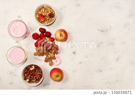 Strawberry and apple smoothies and granola, granola, fresh berries, apples, strawberries and grapes on a pink sunny background. The concept of healthy and natural food. Healthy breakfast, food for 130038873