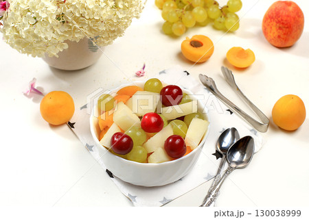 Fruit salad with peach and melon, fresh tropical fruits and berries on a bright sunny table, natural and healthy eating concept, ingredients for a healthy breakfast, detox diet and weight loss, place 130038999
