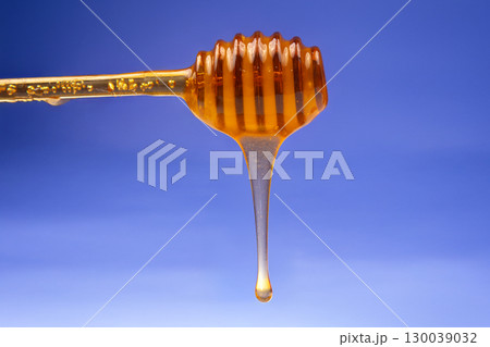 fresh honey dripping from a spoon on a blue background. organic vitamin health food 130039032
