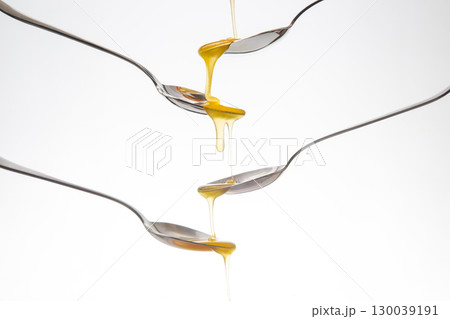 Fresh flower honey drips from a spoon into a spoon on a white background. Organic vitamin food. Fresh flower honey drips from a spoon into a spoon on a white background. Organic vitamin food. 130039191