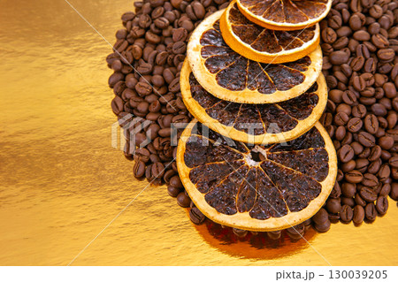 coffee beans and dried orange slices on a shiny golden surface coffee beans and dried orange slices on a shiny golden surface 130039205