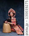 Beautiful Asian woman wearing traditional colorful ethnic costume and silver jewelry, posing in studio portrait. Cultural fashion photography showcasing vibrant embroidery, handmade textile. 130039275