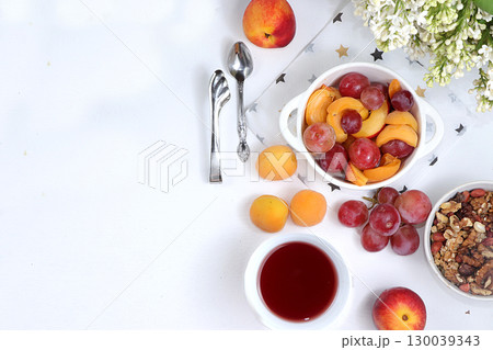 Useful breakfast, food for children, fruit salad with peaches, pears, granola, grapes and flower tea on a bright table. The concept of healthy and natural food. selective focus, top view Useful breakfast, food for children, fruit salad with peaches, pears, granola, grapes and flower tea on a bright table. The concept of healthy and natural food. selective focus, top view 130039343