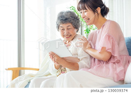 タブレットを見る若い女性とシニア女性 タブレットを見る若い女性とシニア女性 130039374