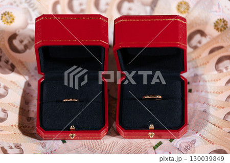 gold rings in red jewelry boxes on currency background for engagement or wedding 130039849