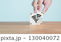 Wi-Fi icon on wooden cube block for service in the cafe. Hand put a wifi icon on wooden cube on wood table. Business communication social network, Wireless network and connection technology concept. 130040072