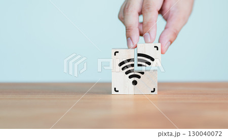 Wi-Fi icon on wooden cube block for service in the cafe. Hand put a wifi icon on wooden cube on wood table. Business communication social network, Wireless network and connection technology concept. 130040072