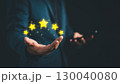Businessman presenting five glowing stars above his hand, symbolizing top-rated customer service, customer satisfaction, or quality assurance in digital marketing and business evaluation concept. 130040080