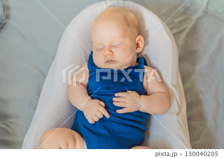 Chubby 3-month-old baby peacefully sleeping in a cozy baby nest at home. Concept of infant comfort, safety, and early development in a warm and nurturing environment 130040205