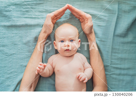 Father hands form a protective roof above baby head. Concept of safety, love, family protection, and emotional security in early childhood Father hands form a protective roof above baby head. Concept of safety, love, family protection, and emotional security in early childhood 130040206