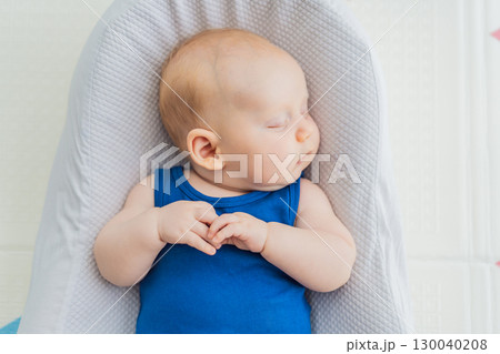 Chubby 3-month-old baby peacefully sleeping in a cozy baby nest at home. Concept of infant comfort, safety, and early development in a warm and nurturing environment 130040208