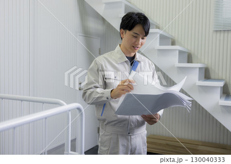 倉庫で図面を見る作業着の男性 130040333