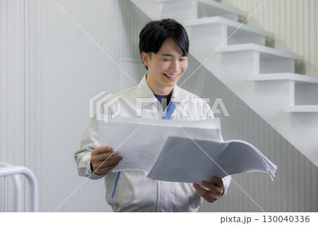 倉庫で図面を見る作業着の男性 130040336