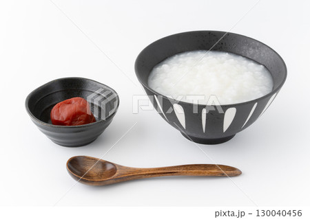 白背景に梅干しとお茶碗に入ったお粥 白背景に梅干しとお茶碗に入ったお粥 130040456