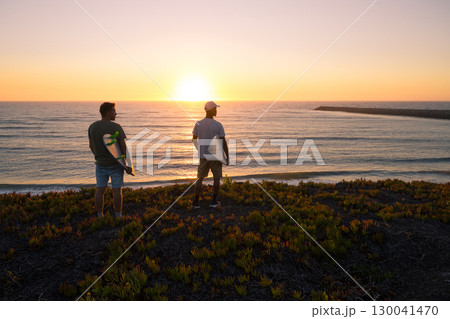 Surfers watching the waves at sunset 130041470