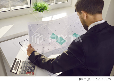Male professional engineer analyzing cadastral map in office Male professional engineer analyzing cadastral map in office 130042029
