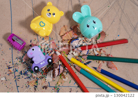 Colored pencils and pencil sharpeners creating colorful shavings on cardboard 130042122