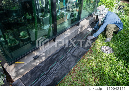 Gardener using black plastic sheeting for preventing weed growth by covered soil. It works by blocking sunlight, which is essential for plant growth, and essentially suffocating weeds. Gardener using black plastic sheeting for preventing weed growth by covered soil. It works by blocking sunlight, which is essential for plant growth, and essentially suffocating weeds. 130042133
