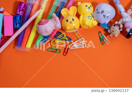 Colorful school supplies forming a border on orange background Colorful school supplies forming a border on orange background 130042137