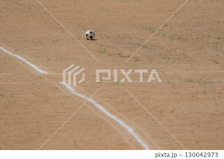 土のグラウンドに転がったサッカーボール 土のグラウンドに転がったサッカーボール 130042973