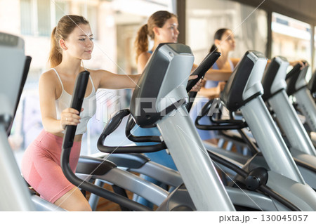Woman training on elliptical machine Woman training on elliptical machine 130045057