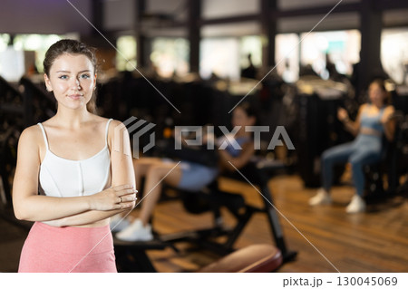 Positive young girl standing in well-equipped gym Positive young girl standing in well-equipped gym 130045069