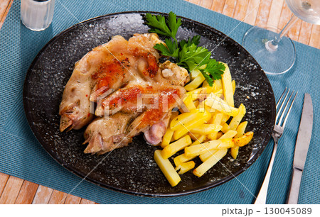 traditional spanish fried pettitoe with fries served on black plate on wooden table 130045089
