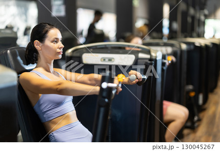 Sportive young girl training on chest press machine in gym Sportive young girl training on chest press machine in gym 130045267