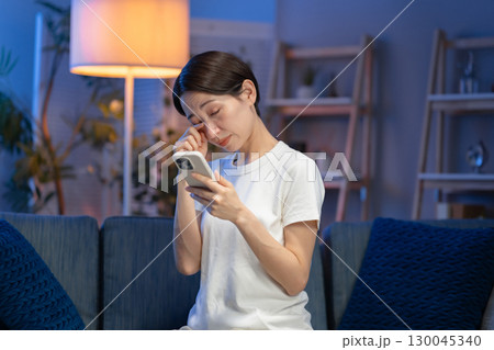 夜にスマホを見る女性 130045340