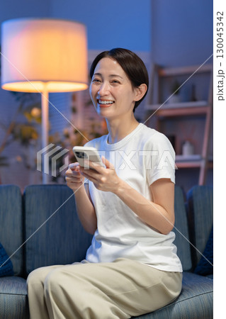 夜にスマホを見る女性 130045342