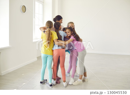 Group of happy children hugging their sports trainer or dance teacher after class Group of happy children hugging their sports trainer or dance teacher after class 130045530