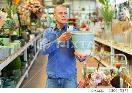 Man photographing flower pot in store 130045575