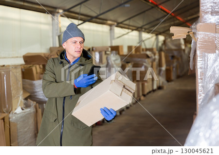 Storekeeper using his phone to take photograph of pasteboard box 130045621