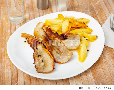 Fried bacon and potatoes on a plate. 130045633