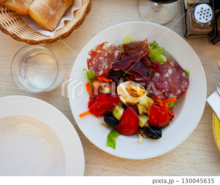 Catalan salad with fresh vegetables, egg and slices of sausages 130045635