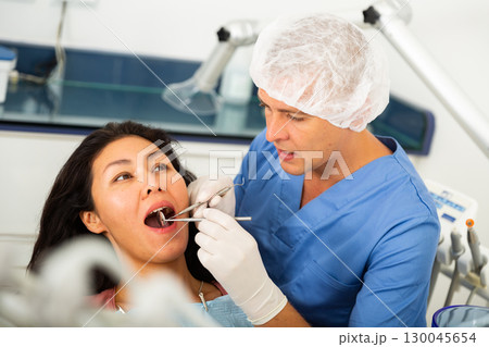 Dentist examining asian female patient teeth Dentist examining asian female patient teeth 130045654