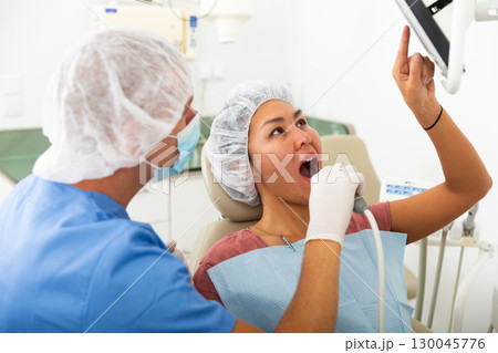 Qualified man dentist conducts an examination of a woman patient using an apexlocator 130045776