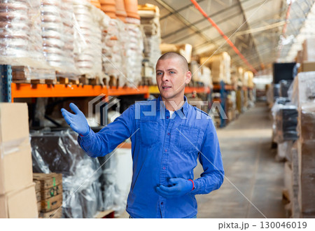 Worker standing in warehouse and making palm gesture 130046019