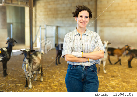 Happy Latin female farmer with crossed hands on chest on goat cattle farm 130046105