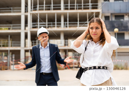 Upset young woman and egineer in construction plant Upset young woman and egineer in construction plant 130046126