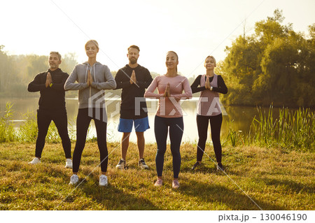 Group of fit and active people doing yoga exercises in nature. Outdoors fitness concept. 130046190