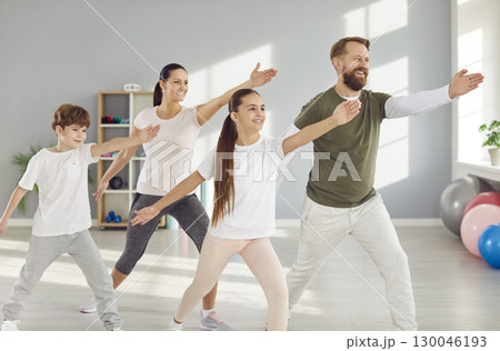 Young smiling sporty parents man and woman doing fit sport exercise with kids in gym 130046193