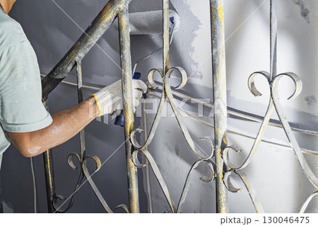 Construction worker in gloves using a paint roller to apply paint to a wall during home renovation. Home renovation project Construction worker in gloves using a paint roller to apply paint to a wall during home renovation. Home renovation project 130046475